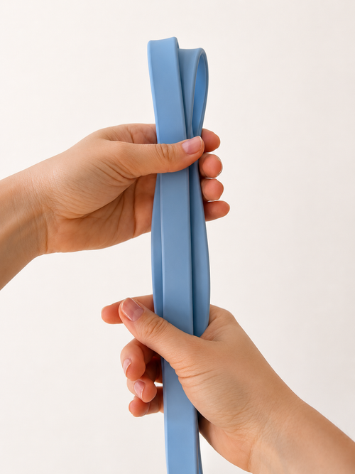 A pair of hands holding a medium blue elastic band or strap against a plain off-white background.